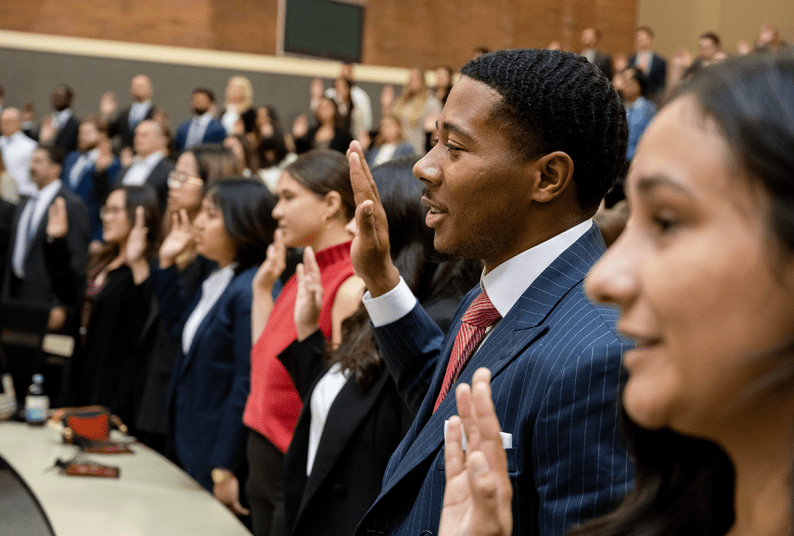 A group of students take an oath and hold up their right hand