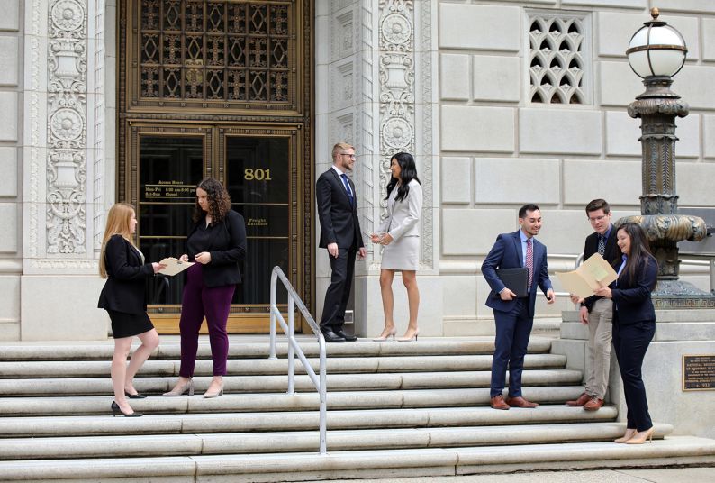 Law students stand on the steps of the Capitol building.