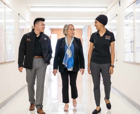Dean Berit Gunderson walking through hallway with two pharmacy students.